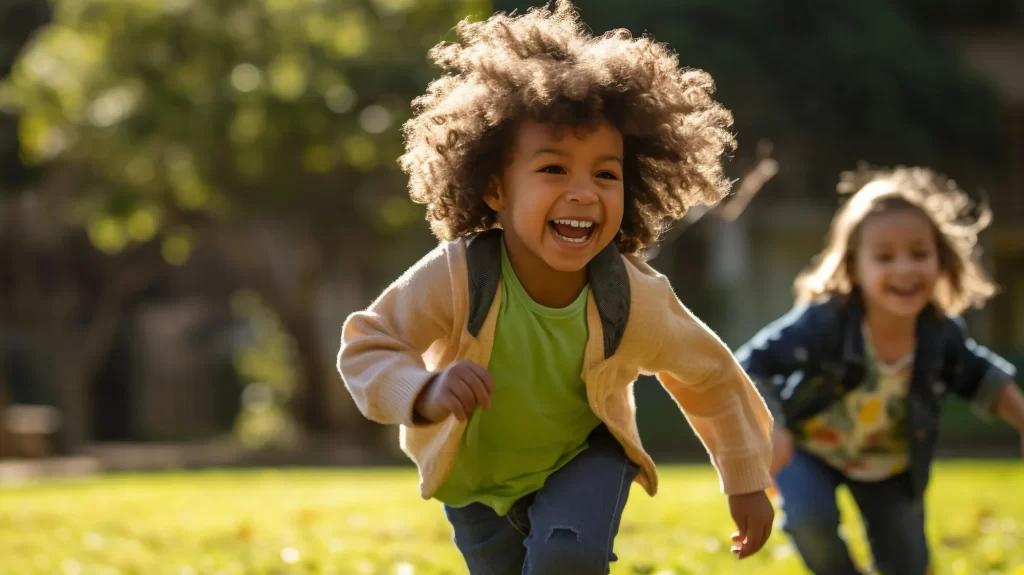 Foto de duas crianças, um menino e uma menina, brincando com árvores ao fundo e um chão gramado